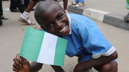 Un enfant brandissant le drapeau nigérian pour accueillir l'équipe nationale de football à l'aéroport d'Abuja le 12 février 2013. La sélection venait de remporter la Coupe d'Afrique des Nations (CAN).   (AFP PHOTO/PIUS UTOMI EKPEI)