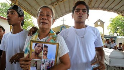 La mère d'un adolescent, tué selon la police par des hommes armés non identifiés, tient le portrait de son fils pendant les funérailles de ce dernier près de Manille le 8 janvier 2017. (REUTERS - Romeo Ranoco)