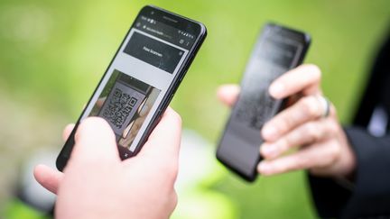 Une personne scanne le QR code d'une autre grâce à son smartphone en Bavière (Allemagne), le 14 mai 2021 (illustration). (MATTHIAS BALK / DPA)