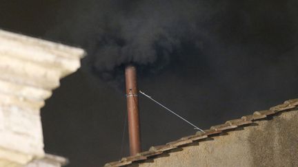 De la fum&eacute;e noire s'&eacute;chappe de la chemin&eacute;e install&eacute;e sur le toit de la chapelle Sixtine indiquant que le premier tour de vote du conclave pour &eacute;lire le pape n'est pas concluant, Vatican, le 12 mars 2013. (TONY GENTILE / REUTERS)