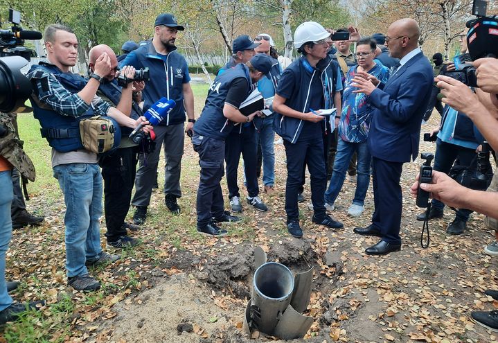 Le&nbsp;directeur de l'AIEA, Rafael Grossi, (casque blanc) avec un représentant russe de Rosatom, devant une roquette&nbsp;tombée dans l'enceinte de la centrale de Zaporijia. (FRANCEINFO / RADIO FRANCE)