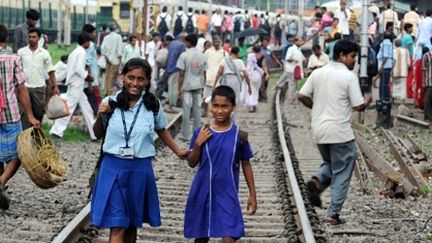 Des élèves marchent sur les rails et des passagers attendent un train bloqué par la panne à Calcutta (31-7-2012). (AFP - Dibyangshu SARKAR)