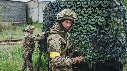 Des soldats ukrainiens se tient près d'un véhicule camouflé dans la région de Donestk, le 14 mai 2022. (DIEGO HERRERA CARCEDO / ANADOLU AGENCY / AFP)