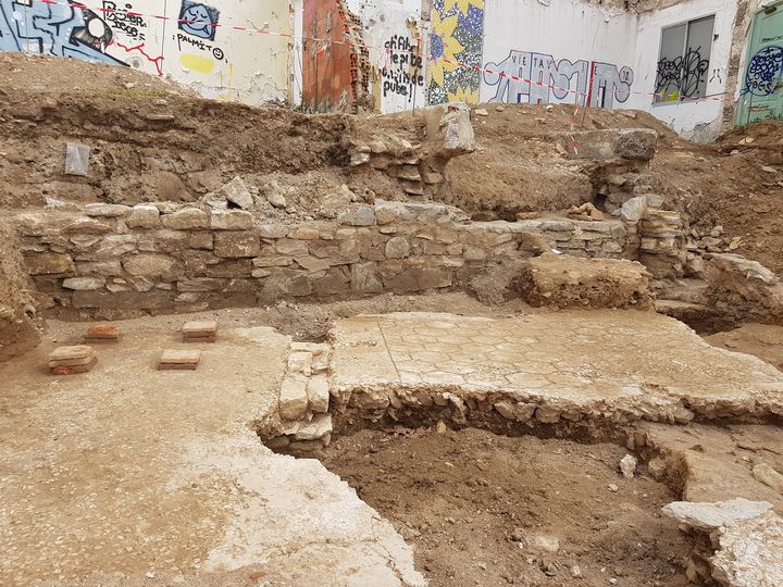 Tranche 2. Deux pièces d’une domus datée des Ier/IIe siècles de notre ère. On a découvert dans l’une, à gauche sur le cliché, des pilettes d’hypocauste permettant la circulation d’air chaud sous le sol (disparu) qu’elles soutenaient. À droite, le sol de la pièce voisine présente un décor géométrique en nid d’abeille fait de tesselles noires. Au premier plan, une grande fosse d’époque moderne a recoupé ces bétons de sols antiques en faisant disparaître l’accès qui reliait les deux pièces. (CHARLOTTE GLEIZE / INRAP)