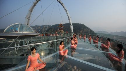 Ces Chinoises tout d'orange vêtues, bustes droit et jambes repliées en tailleur, marquent elles aussi la journée du yoga sur une plateforme en verre dans la banlieue de Pékin, capitale de la Chine. (CHINA STRINGER NETWORK / REUT)