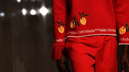 Une danseur de claquettes a accompagné le défilé de la marque Off-White de l'Américain Virgil Abloh, de retour à la Fashion week de Paris après un burn-out, avec silhouettes fluides et couleurs vitaminées. Le danseur Cartier Williams portant un T-shirt "I support young black businesses" (je soutiens les jeunes entrepreneurs noirs) a ouvert le show en faisant une apparition depuis les coulisses situées au milieu de la salle, dans une scénographie atypique. Tout de noir vêtu et dans le noir, le créateur hyperactif, star des millenials, Virgil Abloh est apparu à la fin du show pour saluer le public après avoir été absent de la précédente semaine de la mode parisienne cet automne, contraint au télé-travail sur prescription médicale.  Ce défilé avant celui, jeudi, de la marque du luxe français Louis Vuitton - dont le styliste afro-américain dirige les collections pour homme - était très attendu, d'autant plus que ce roi de la "streetwear" a prédit dans une récente interview la mort de cette tendance.  Les hommes Off-White portaient effectivement beaucoup de chaussures conventionnelles même si le créateur n'a pas raté l'occasion de promouvoir les baskets Off-White x Air Jordan 5, parmi les plus convoités. Des looks poétiques avec des chemises à rubans surmontant des pantalons fluides alternaient avec des costumes structurés rouge, vert ou bleu néon, à trous, un détail déjà omniprésent dans la collection prêt-à-porter femme de septembre.  (ANNE-CHRISTINE POUJOULAT / AFP)