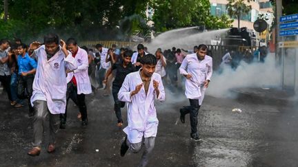 Des étudiants en médecine aspergés par des canons à eau de la police, lors d'une manifestation pour demander la démission du président, à Colombo (Sri Lanka), le 29 mai 2022. (ISHARA S. KODIKARA / AFP)