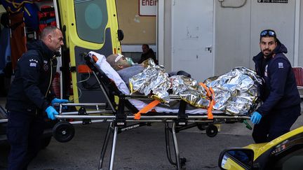 Medical staff transport on a stretcher a survivor of the cargo ship which sank off the island of Lesvos, November 26, 2023. (MANOLIS LAGOUTARIS / AFP)