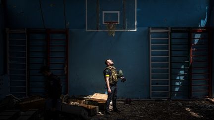 Un policier dans le village de Vilkhivka, récemment repris par l'armée ukrainienne, près de la ville orientale de Kharkiv, le 13 mai 2022. (DIMITAR DILKOFF / AFP)