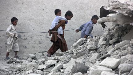 Des enfants marchent dans les gravats, apr&egrave;s le s&eacute;isme survenu le 24 septembre 2013 au Baloutchistan, une r&eacute;gion recul&eacute;e du Pakistan.&nbsp; (REUTERS)