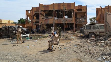 Un soldat malien se tient à côté d'un bâtiment détruit et de voitures brûlées, le 13 novembre 2018 à Gao, après un attentat-suicide à la voiture piégée qui a fait trois morts. (STR / AFP)