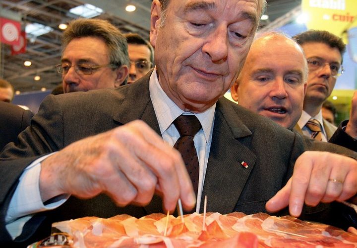 Jacques Chirac, alors pr&eacute;sident de la R&eacute;publique, d&eacute;guste du jambon au Salon de l'agriculture, &agrave; Paris,&nbsp;le 25 f&eacute;vrier 2006. (OLIVIER LABAN-MATTEI / AFP)