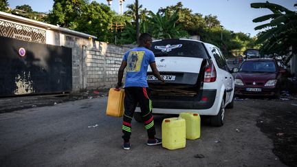 Un habitant charge des bidons d'eau dans sa voiture, le 23 mai 2023 à Koungou (Mayotte). (PHILIPPE LOPEZ / AFP)