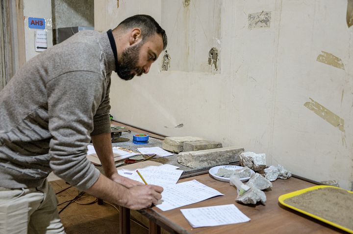 Un employé du musée de Mossoul, au Nord de l'Irak, analyse les fragments antiques retrouvés, le 14 décembre 2021 (ZAID AL-OBEIDI / AFP)