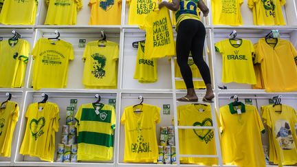 Une vendeuse installe des maillots de football dessin&eacute;s &agrave; l'occasion de la Coupe du monde 2014 &agrave; Rio de Janeiro (Br&eacute;sil), le 20 mai 2014. (YASUYOSHI CHIBA / AFP)