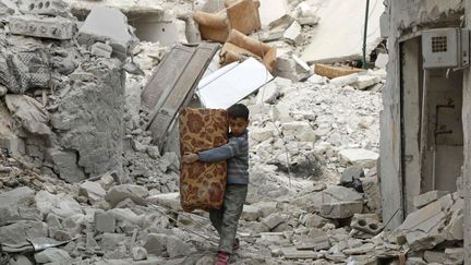 Un jeune gar&ccedil;on transporte ses affaires parmi des d&eacute;combres &agrave; Alep (Syrie), le 17 novembre 2014. (HOSAM KATAN / REUTERS)