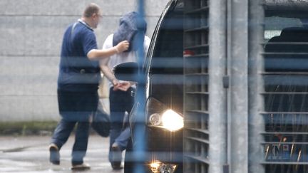 Un policier escorte l'un des deux fonctionnaires de la brigade des stups suspect&eacute; du vol de 52 kg de coca&iuml;ne au si&egrave;ge de la police judiciaire, &agrave; Paris, le 6 ao&ucirc;t 2014. (KENZO TRIBOUILLARD / AFP)