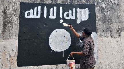 En Indon&eacute;sie, un employ&eacute; du gouvernement recouvre de peinture un drapeau du groupe&nbsp;Etat islamique, le 5 ao&ucirc;t&nbsp;2014. (CITIZENSIDE / AGOES RUDIANTO / AFP)