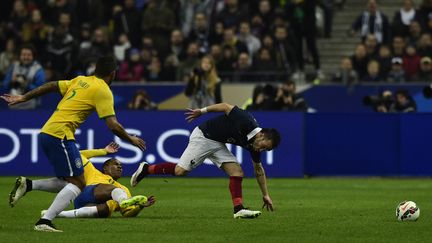 Le milieu fran&ccedil;ais Mathieu Valbuena tr&eacute;buche apr&egrave;s un tacle du Br&eacute;silien Elias,&nbsp;jeudi 26 mars, au Stade de France (Saint-Denis). (FRANCK FIFE / AFP)