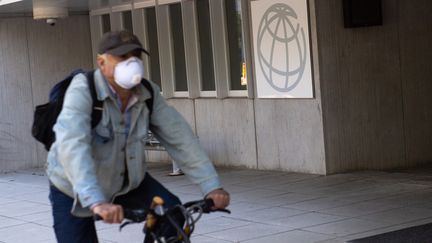 Un homme masqué passe en vélo devant un des bâtiments de la Banque mondiale à Washington (Etats-Unis), le 15 avril 2020. (SAUL LOEB / AFP)