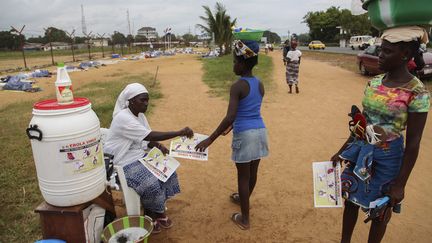 &nbsp; (Une femme distribue des informations sur le virus Ebola, au Liberia, le 12 août. © MaxPPP)