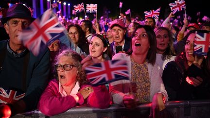 Des membres du public agitent des drapeaux britanniques devant le palais de Buckingham, lors de la BBC Platinum Party, le 4 juin 2022. (DANIEL LEAL / AFP)