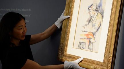 Sharon Kim, directrice chez Christie&#039;s, accroche les &quot;Joueurs de cartes&quot;, aquarelle de Cézanne en vente le 1er mai 2012
 (Don Emmert / AFP)