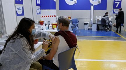 Un homme se fait vacciner avec le vaccin Pfizer-BioNtech contre le Covid-19, dans le parking d'un centre commercial, à Tel Aviv (Israël), le 26 janvier 2021. (JACK GUEZ / AFP)