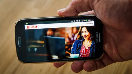 Un homme consulte le service de vid&eacute;o &agrave; la demande Netflix sur son smartphone &agrave; Stockholm&nbsp;(Su&egrave;de) le 11 septembre 2014. (JONATHAN NACKSTRAND / AFP)