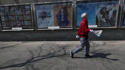 Un homme muni d'un masque de protection passe à côté d'un cinéma fermé à Pékin, le 6 avril 2020 (ANDY WONG / AP / SIPA)