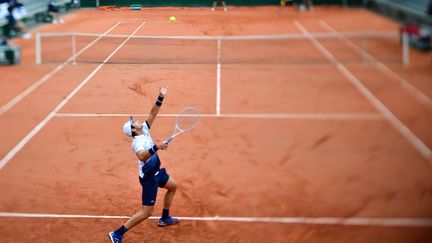 Le Français Elliot Benchetrit sert, lors du premier jour du tournoi de Roland-Garros, le 27 septembre 2020 à Paris, contre l'Américain&nbsp;John Isner. (MARTIN BUREAU / AFP)