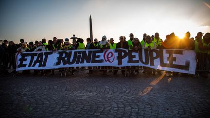 Des "gilets jaunes" affichent le slogan "L'Etat ruine le peuple", lors d'un blocage place de la Concorde, à Paris, le 17 novembre 2018. (VALENTINA CAMU / HANS LUCAS / AFP)