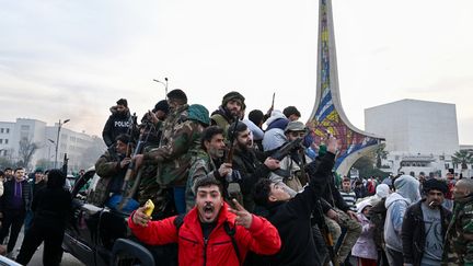 Des manifestants célèbrent la chute du régime de Bachar al-Assad à proximité des troupes rebelles, sur la place des Omeyyades à Damas, le 8 décembre 2024. (LOUAI BESHARA / AFP)