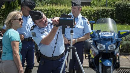 Un gendarme pr&eacute;sente &agrave; une conductrice un nouveau mod&egrave;le de radar, le 29 juin 2012 sur l'aire de M&acirc;con-Saint-Albain (Sa&ocirc;ne-et-Loire). (JEAN-PHILIPPE KSIAZEK / AFP)