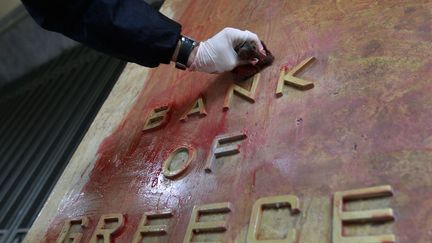 Un employ&eacute; nettoie la fa&ccedil;ade de la banque de Gr&egrave;ce &agrave; Ath&egrave;nes, le 16 f&eacute;vrier 2012. (JOHN KOLESIDIS / REUTERS)