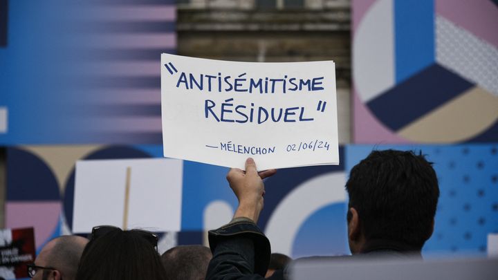 Un manifestant porte une pancarte faisant référence à une déclaration de Jean-Luc Mélenchon, lors d'un rassemblement contre l'antisémitisme, après l'affaire du viol de Courbevoie, le 19 juin 2024 à Paris. (MAGALI COHEN / HANS LUCAS / AFP)