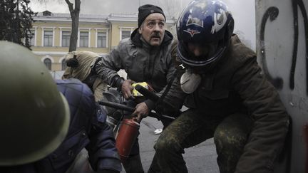 De nombreux coups de feu ont &eacute;t&eacute; entendus sur le Ma&iuml;dan. Les manifestants se prot&eacute;geaient tant bien que mal. (REUTERS)