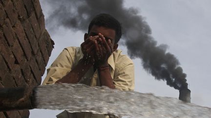 Un ouvrier boit de l'eau devant une usine de briques &agrave; Togga, dans le nord de l'Inde, le 6 d&eacute;cembre 2009. (AJAY VERMA / REUTERS)