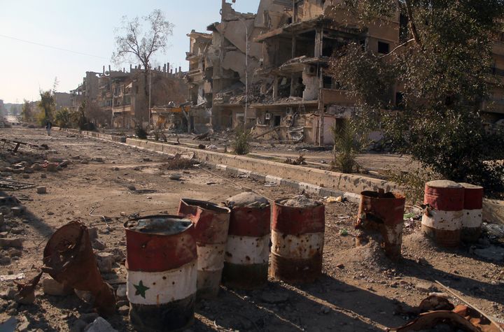 Des barils peints aux couleurs du drapeau syrien barrent une rue de Deir Ezzor (Syrie) d&eacute;vast&eacute;e par les combats, le 7 f&eacute;vrier 2014. (AHMAD ABOUD / AFP)