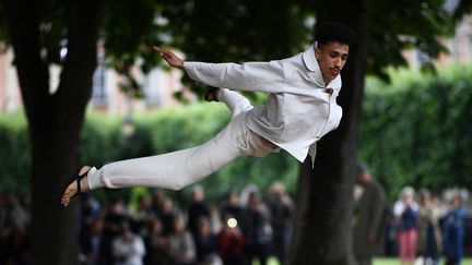 Un mannequin présente de façon athlétique et poétique une création de la maison Issey Miyake durant la Fashion Week Homme printemps/été 2019 à Paris. (ANNE-CHRISTINE POUJOULAT / AFP)