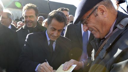 Nicolas Sarkozy signe un autographe apr&egrave;s avoir rendu hommage au g&eacute;n&eacute;ral De Gaulle &agrave; l'occasion du 41e anniversaire de sa mort,&nbsp;&agrave; Colombey-les-Deux-Eglises (Haute-Marne), le 9 novembre 2011. (ERIC FEFERBERG / AFP)