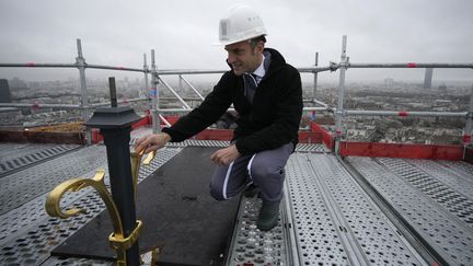 Le président de la République Emmanuel Macron touche le haut de la nouvelle flèche de la cathédrale Notre-Dame de Paris le 8 décembre 2023. (CHRISTOPHE ENA / POOL)