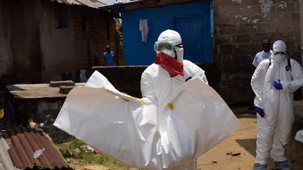 Au Liberia, des travailleurs de la Croix-Rouge emportent le corps d'un b&eacute;b&eacute; de 18 mois victimes du virus d'Ebola, le 12 septembre 2014. (ZOOM DOSSO / AFP)