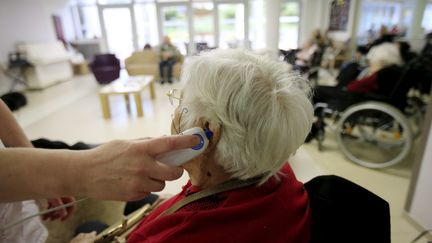 Une soignante prend la température d'une résidente d'un ehpad, durant la crise sanitaire. Photo d'illustration. (FRANTZ BOUTON / MAXPPP)