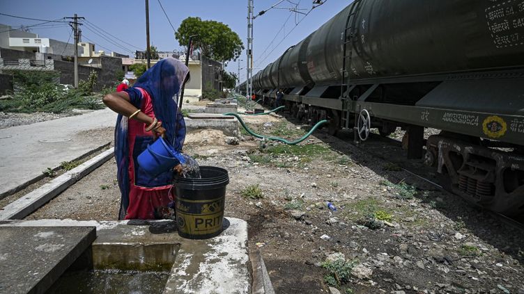 11 mai 2022. En Inde, à Pali, une femme remplit son seau avec une eau livrée par train spécial, en cette journée d'été caniculaire. Chaque jour, des dizaines de villageois, le plus souvent des femmes et des enfants, attendent avec un jerrycan bleu et des seaux, que ce train leur apporte cette eau précieuse, au coeur de cette vague caniculaire dans l'état désertique du Rajasthan. (PRAKASH SINGH / AFP)