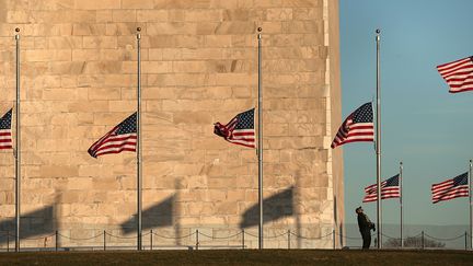 Un employ&eacute; baisse les drapeaux du Washington Monument &agrave; la moiti&eacute; de leur base. Le pr&eacute;sident Obama a ordonn&eacute; la mise en berne des drapeaux en signe de deuil.&nbsp; (WIN MCNAMEE / GETTY IMAGES NORTH AMERICA)