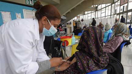 Une femme âgée reçoit une dose du vaccin Pfizer-BioNTech&nbsp;contre le coronavirus&nbsp;Covid-19,&nbsp; alors que d'autres attendent leur tour dans la salle de sport El-Menzah de Tunis,&nbsp; le 3 mai 2021. (FETHI BELAID / AFP)