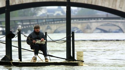 Un artiste dessine au bord de la Seine en crue à Paris le 4 mai 2001. (PHILIPPE DESMAZES / AFP)