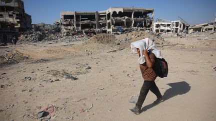 A child walks past destroyed buildings in eastern Gaza City on July 10, 2024. (OMAR AL-QATTAA / AFP)