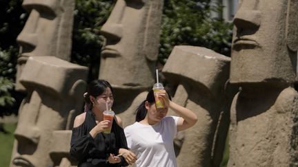 Des femmes se rafraichissent à Pékin, alors que la capitale chinoise est frappée par une vague de chaleur, le 21 juin 2023. (ANDY WONG / AP / SIPA)